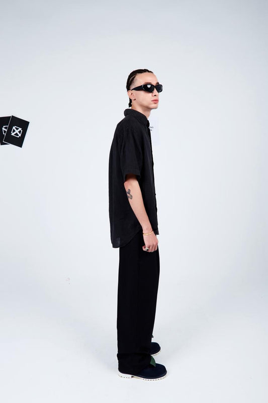 Person wearing a black outfit with sunglasses on a white background