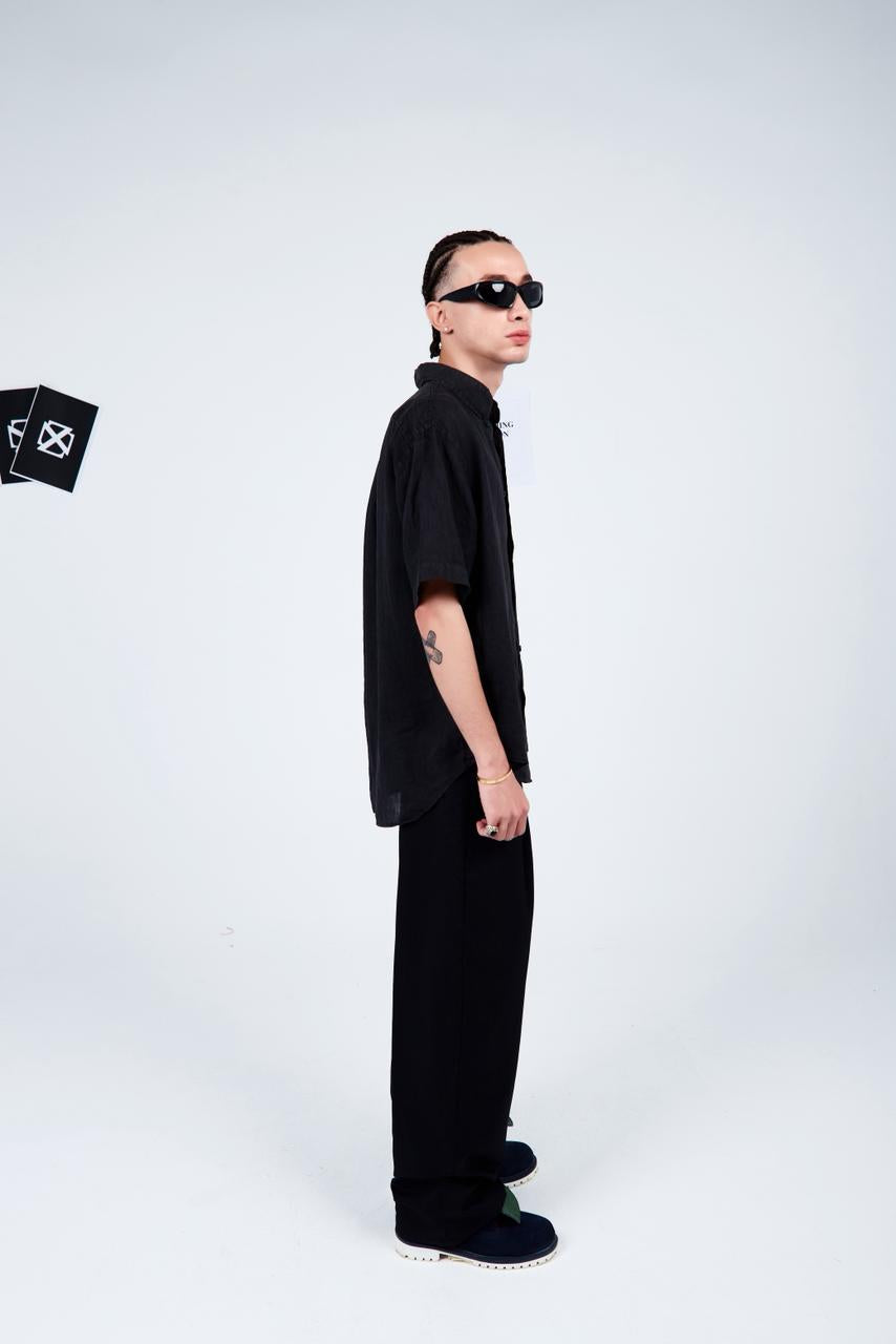 Person wearing a black outfit with sunglasses on a white background